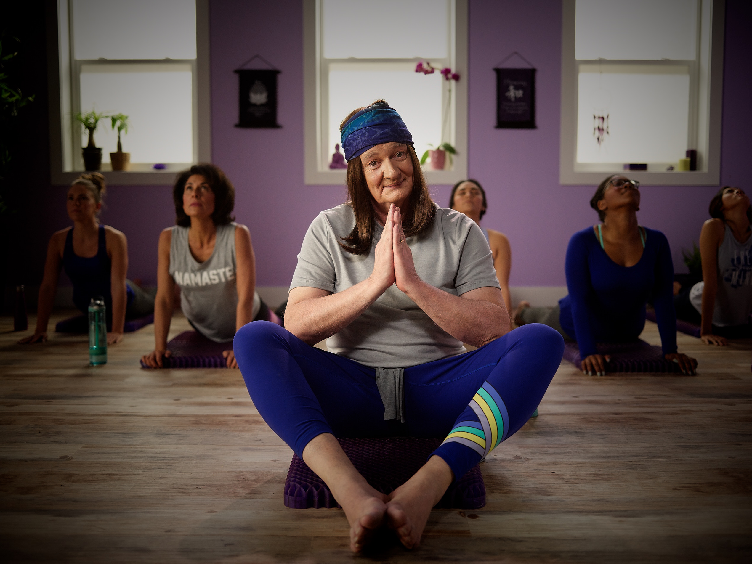 COLIN MOCHRIE AS A YOGIE DOING YOGA ON A PURPLE SEAT CUSHION