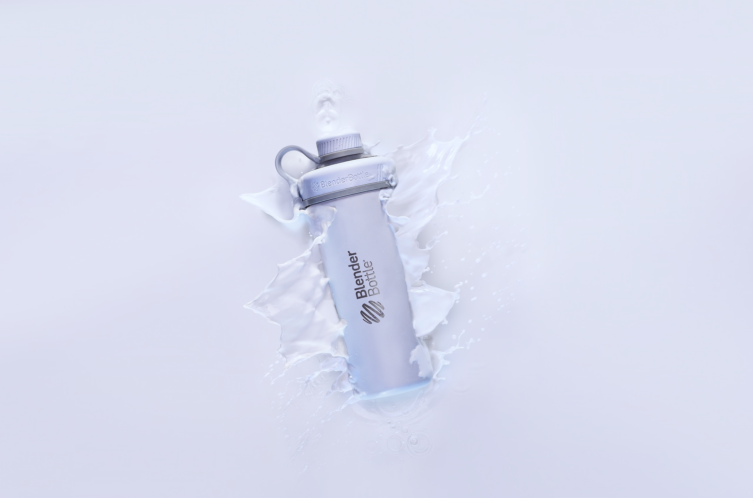 SPORTS BOTTLE SPLASHING INTO WHITE LIQUID WATER FROM ABOVE