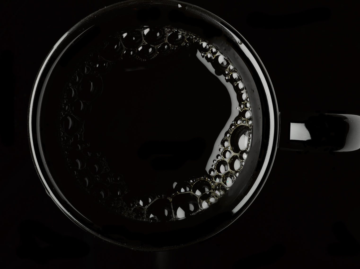 Coffee in a black cup from above on a black background