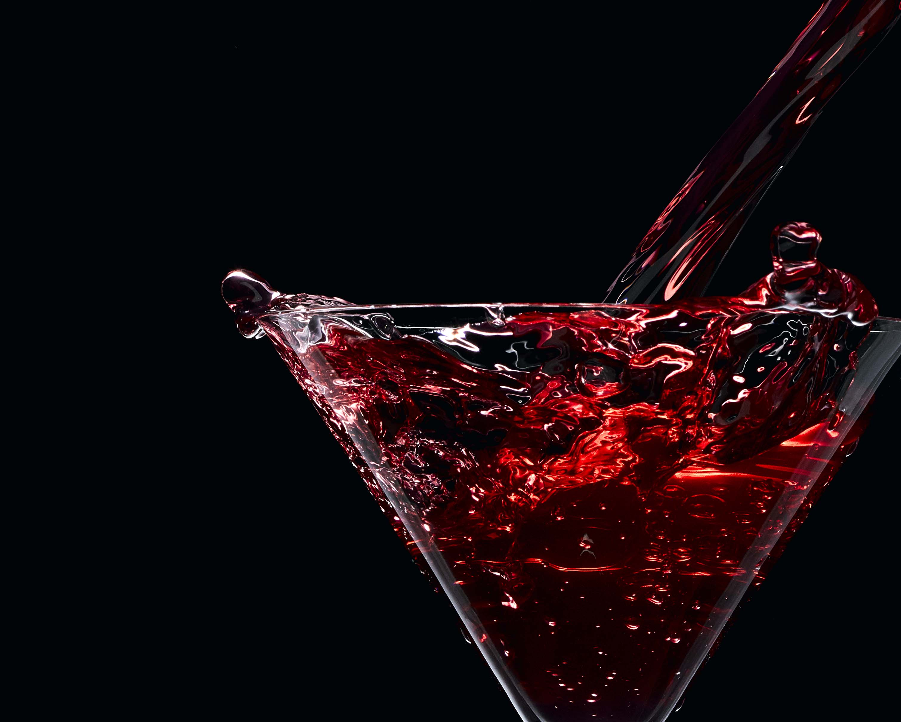 Mix red alcohol drink pouring into glass with a splash and black background